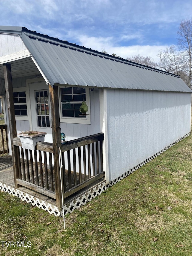 view of side of property featuring a wooden deck, a lawn, and metal roof