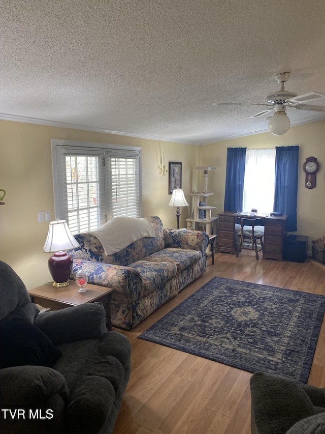 living room featuring ceiling fan, crown molding, wood finished floors, and a textured ceiling