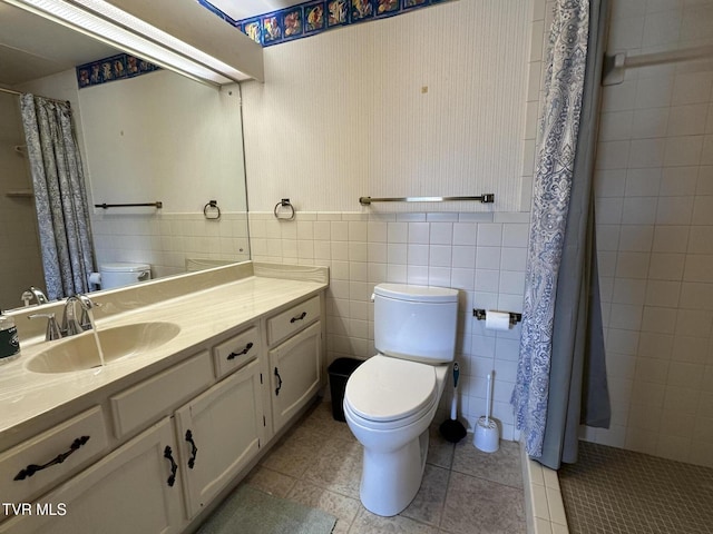 bathroom with vanity, a tile shower, tile walls, toilet, and tile patterned floors