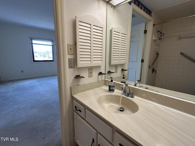 full bath featuring baseboards, vanity, and a tile shower