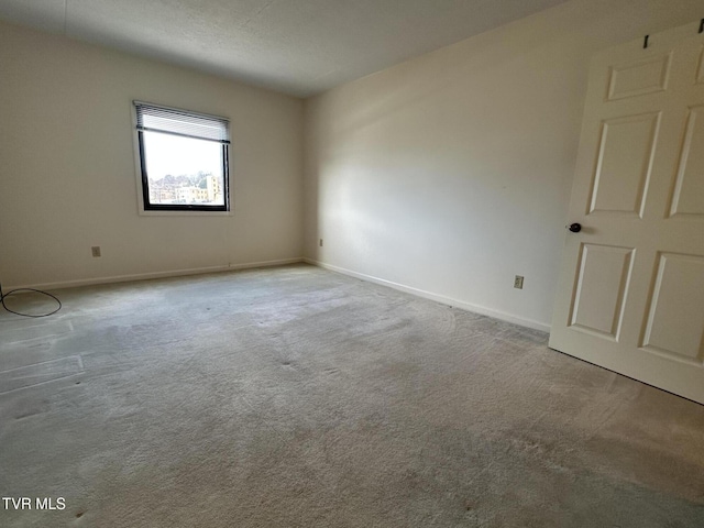 spare room featuring carpet flooring and baseboards