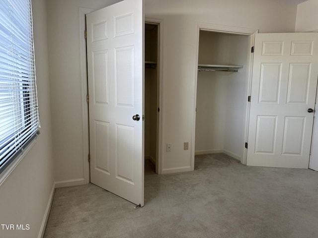 unfurnished bedroom featuring baseboards, a closet, and light carpet