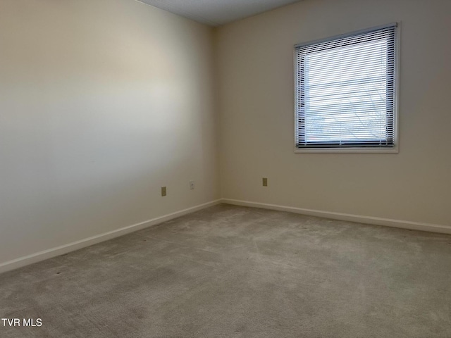 carpeted spare room featuring baseboards