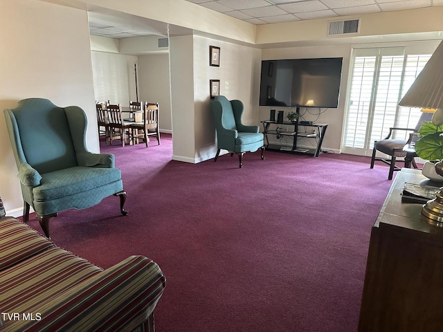 living area featuring visible vents, baseboards, a paneled ceiling, and carpet