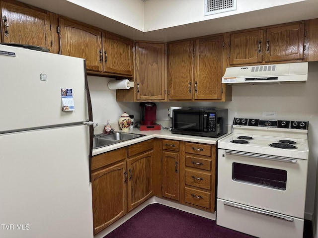 kitchen with white appliances, brown cabinetry, visible vents, light countertops, and under cabinet range hood