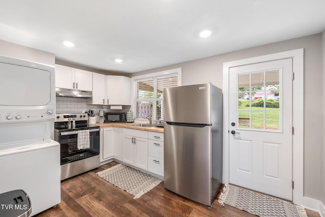 kitchen with under cabinet range hood, stacked washer and dryer, dark wood-style flooring, stainless steel appliances, and a sink