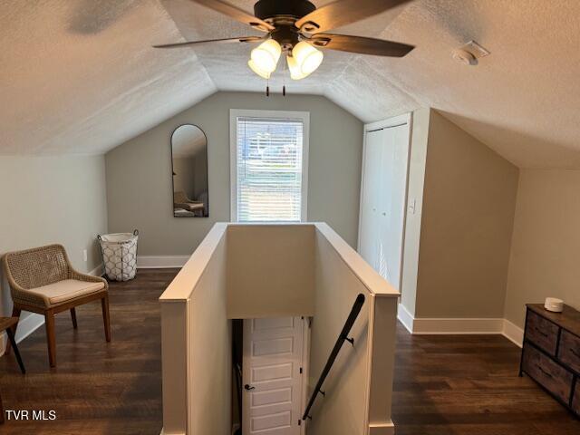 additional living space with baseboards, a textured ceiling, lofted ceiling, and dark wood-style flooring