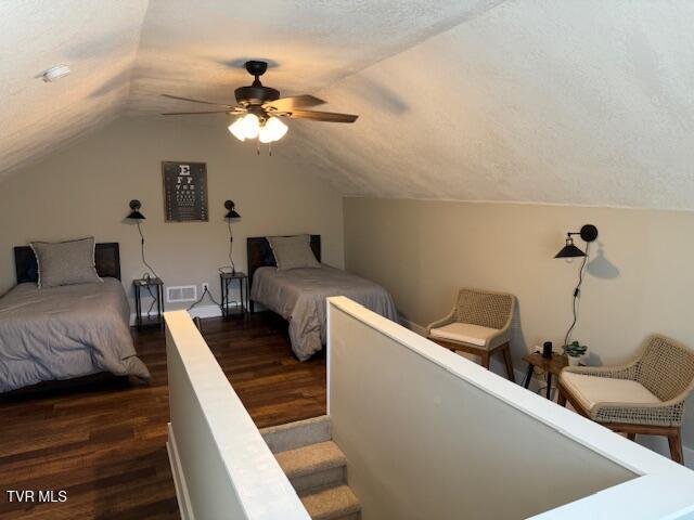 bedroom featuring visible vents, dark wood finished floors, vaulted ceiling, a textured ceiling, and a ceiling fan