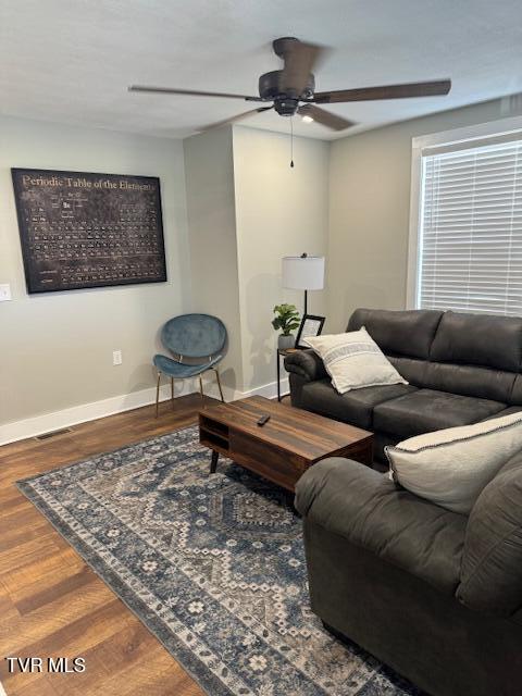 living area with a ceiling fan, visible vents, wood finished floors, and baseboards