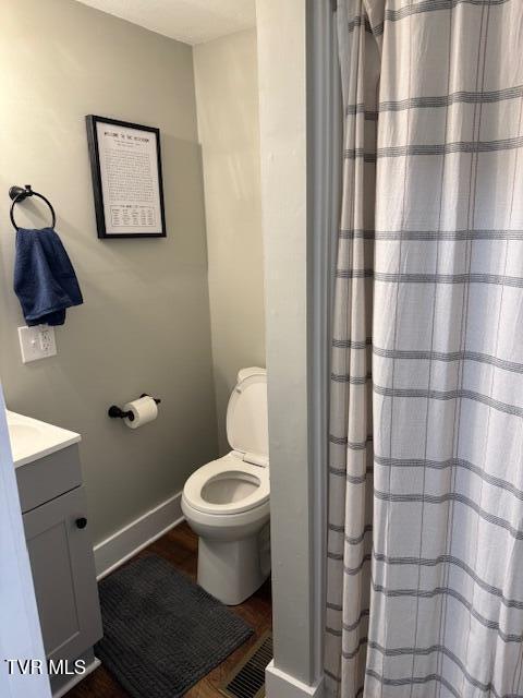 bathroom featuring a shower with curtain, toilet, wood finished floors, baseboards, and vanity