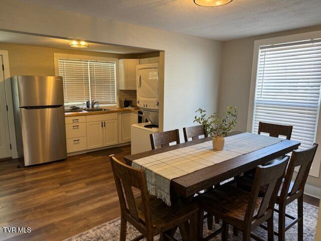 dining room featuring dark wood-type flooring and stacked washing maching and dryer