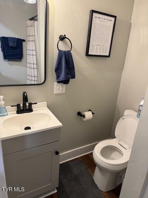 bathroom with baseboards, toilet, and vanity