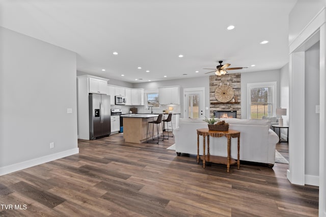 kitchen with a center island, open floor plan, appliances with stainless steel finishes, dark wood-style floors, and white cabinets