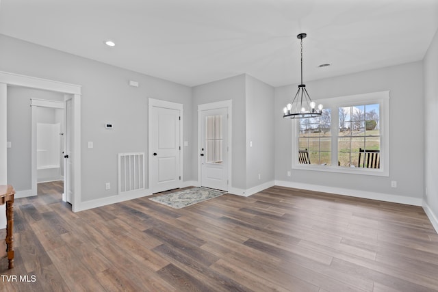 unfurnished dining area with visible vents, baseboards, a chandelier, and dark wood finished floors