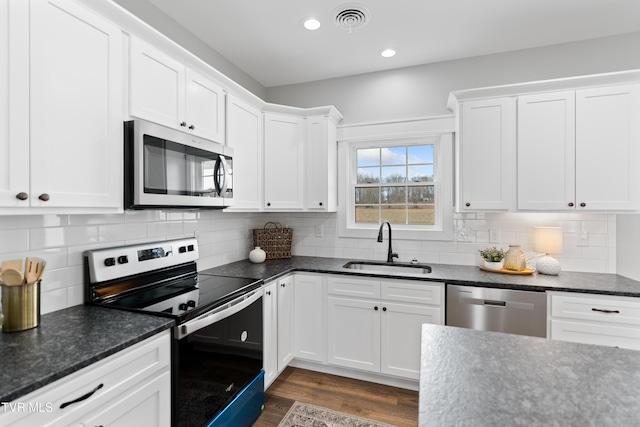 kitchen with visible vents, dark wood finished floors, white cabinets, stainless steel appliances, and a sink