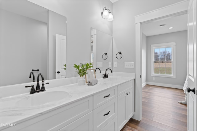 full bathroom with double vanity, wood finished floors, baseboards, and a sink