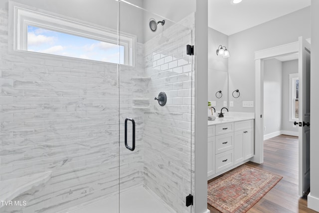 full bath featuring baseboards, wood finished floors, a stall shower, and vanity