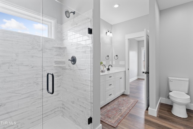 bathroom featuring toilet, a stall shower, wood finished floors, baseboards, and vanity