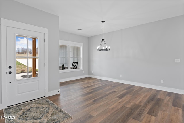 foyer entrance with baseboards, an inviting chandelier, and dark wood finished floors