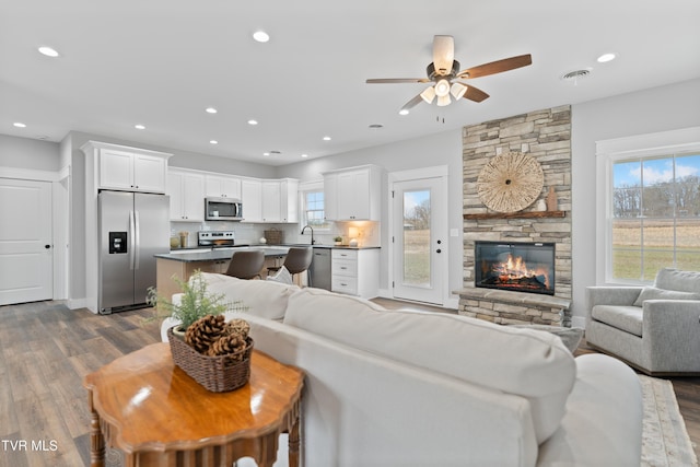 living room with a fireplace, recessed lighting, dark wood-style floors, and visible vents