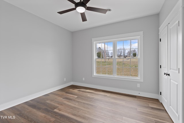 unfurnished bedroom featuring visible vents, a ceiling fan, wood finished floors, a closet, and baseboards