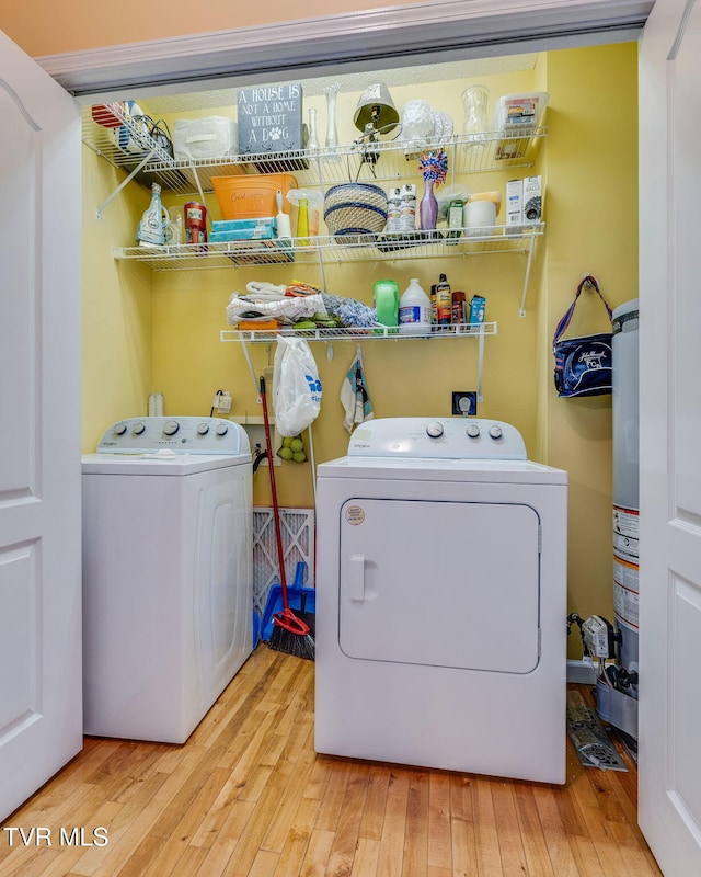 laundry room with laundry area, hardwood / wood-style flooring, water heater, and washing machine and clothes dryer