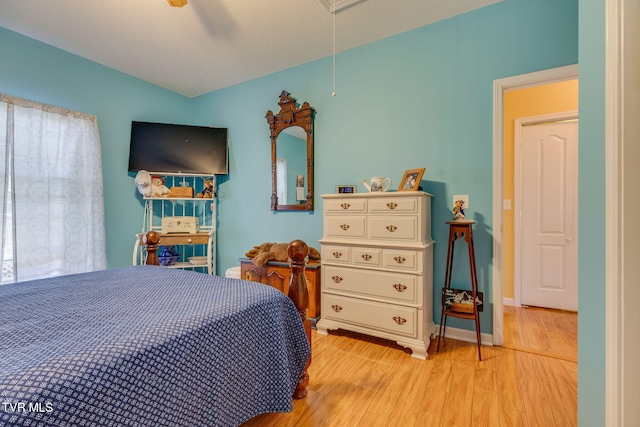 bedroom featuring a ceiling fan, attic access, light wood-style floors, and baseboards