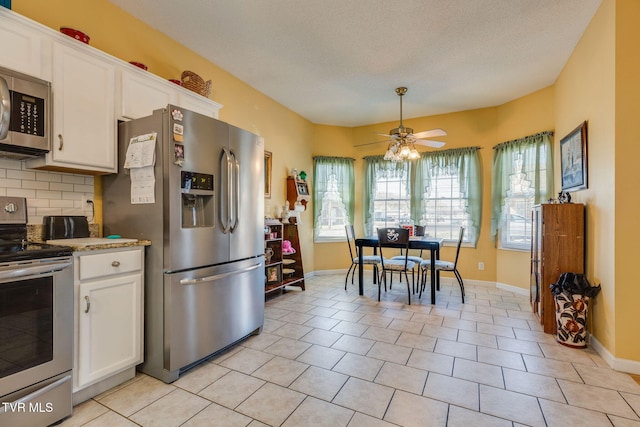 kitchen with decorative backsplash, white cabinetry, stainless steel appliances, and baseboards