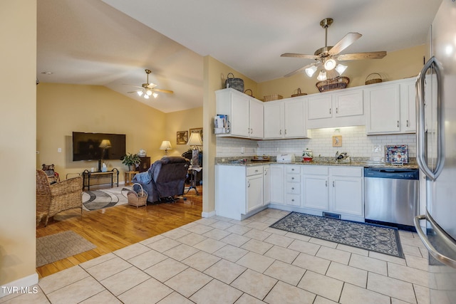 kitchen featuring open floor plan, white cabinets, appliances with stainless steel finishes, and decorative backsplash