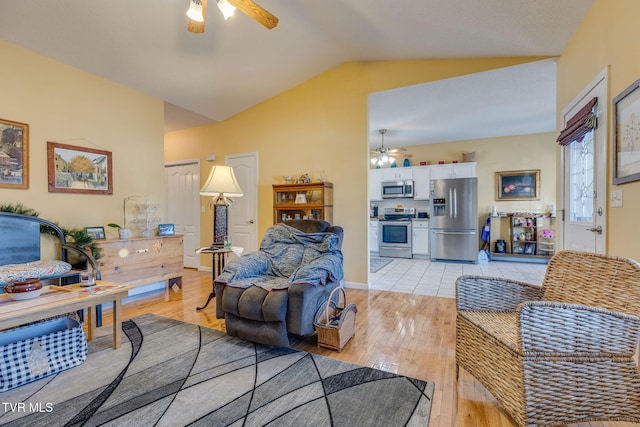 living room featuring light wood finished floors, a ceiling fan, and vaulted ceiling