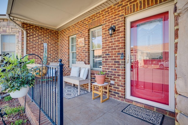 doorway to property featuring brick siding and covered porch