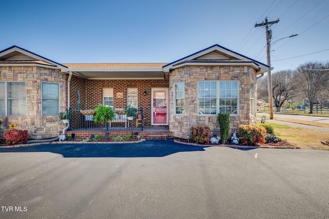 view of front of property with brick siding, stone siding, and a porch