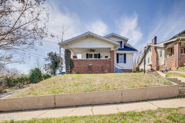 bungalow-style home with a front lawn, brick siding, and a ceiling fan