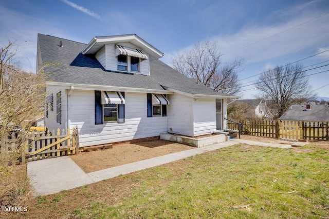 bungalow featuring a shingled roof, a front lawn, and fence