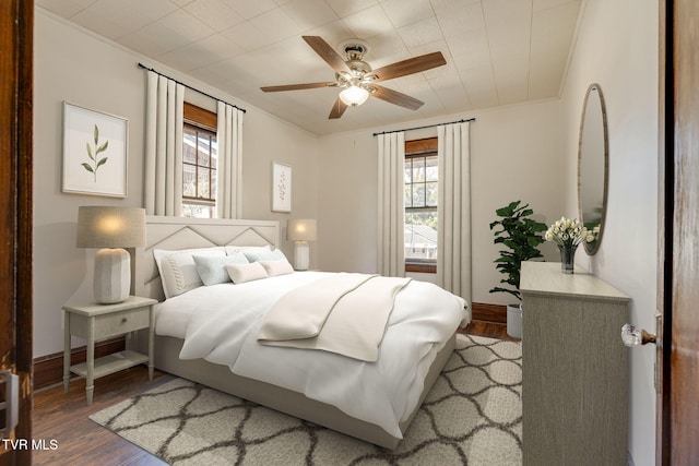 bedroom featuring crown molding, multiple windows, wood finished floors, and ceiling fan