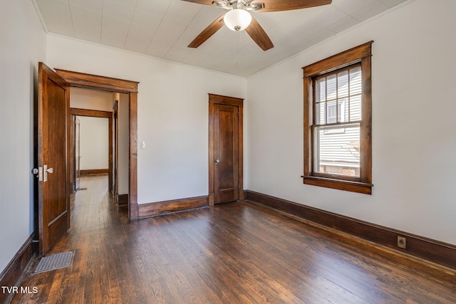 unfurnished bedroom with visible vents, a ceiling fan, crown molding, baseboards, and dark wood-style flooring