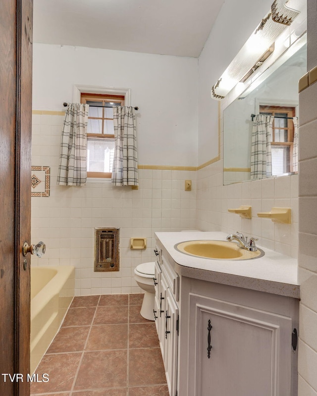 full bath featuring vanity, heating unit, tile patterned floors, toilet, and a bathtub