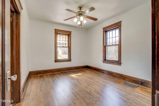 spare room featuring visible vents, wood-type flooring, baseboards, and a ceiling fan