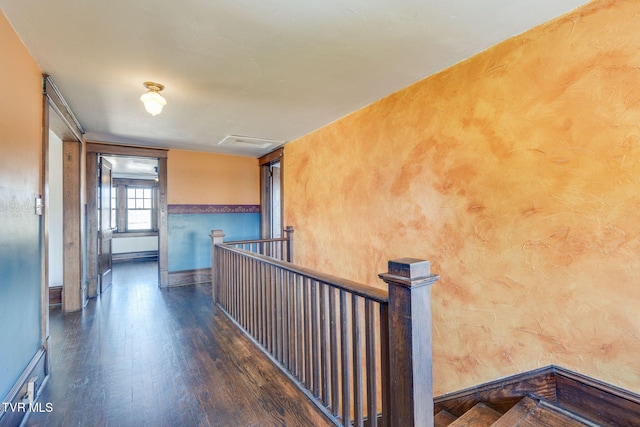 hallway with baseboards, an upstairs landing, attic access, and wood finished floors