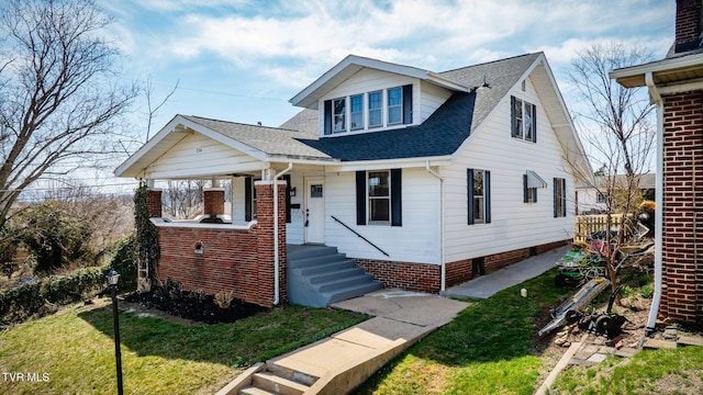 bungalow-style home featuring roof with shingles and a front lawn