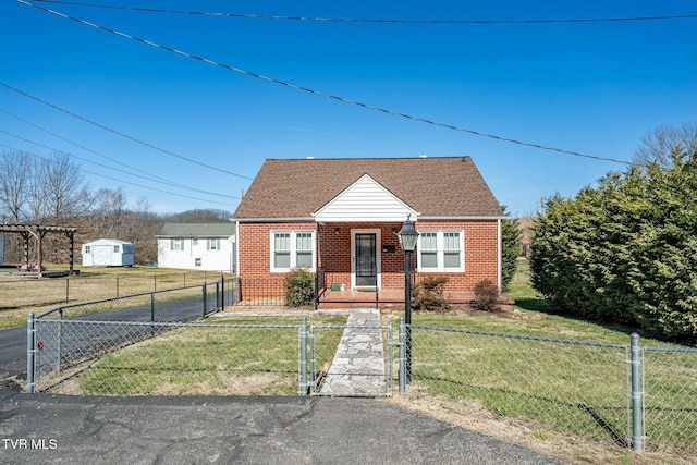 view of front of home with a gate, a fenced front yard, roof with shingles, a front yard, and brick siding