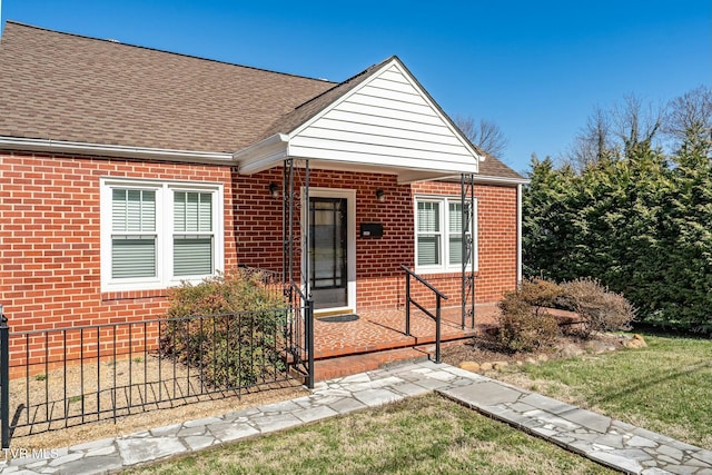 view of front of home with brick siding and roof with shingles