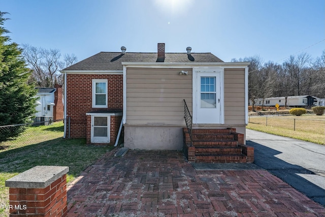 back of property with entry steps, fence, a lawn, and a chimney