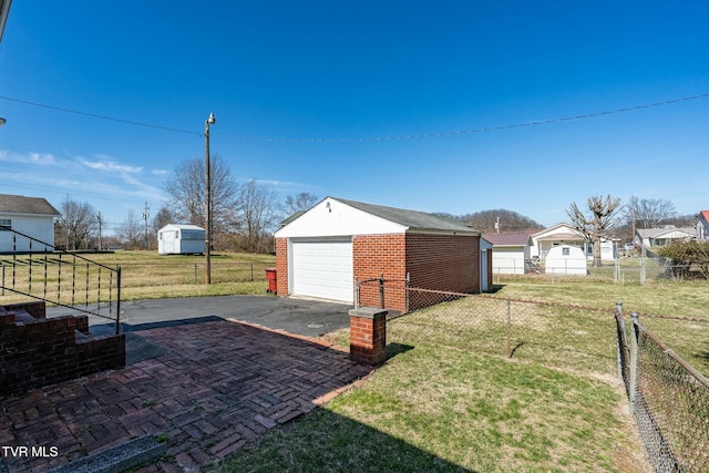 view of yard with aphalt driveway, a garage, an outdoor structure, and fence