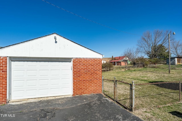 garage with aphalt driveway, a gate, and fence