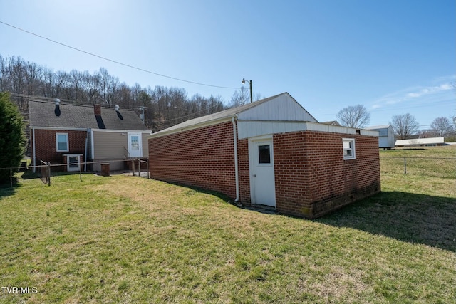 rear view of property with an outdoor structure, a yard, fence, and brick siding