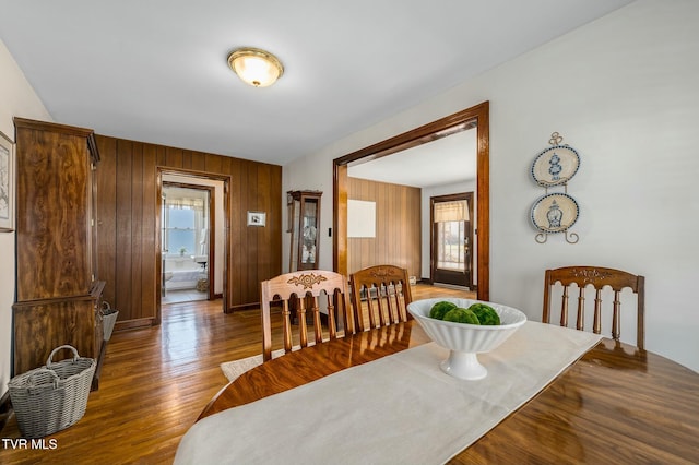 dining area with wood finished floors and wood walls