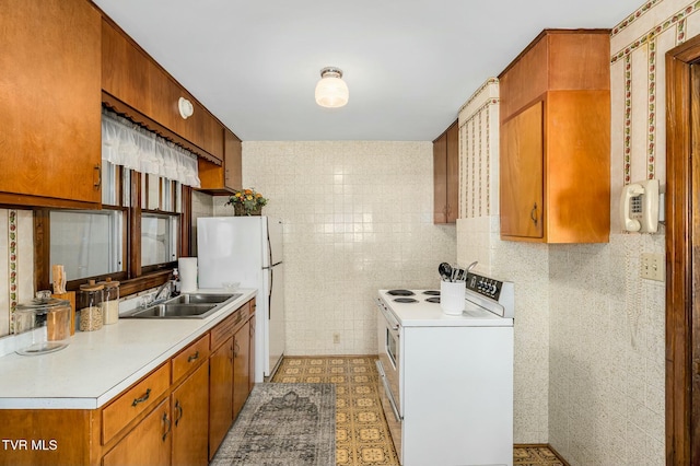 kitchen with a sink, white appliances, tile walls, brown cabinetry, and light countertops