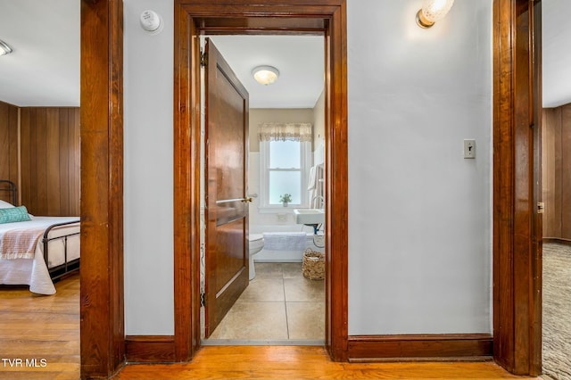 corridor with wood walls, baseboards, and wood finished floors