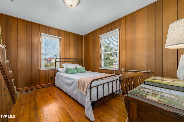 bedroom with visible vents, wood walls, and hardwood / wood-style flooring